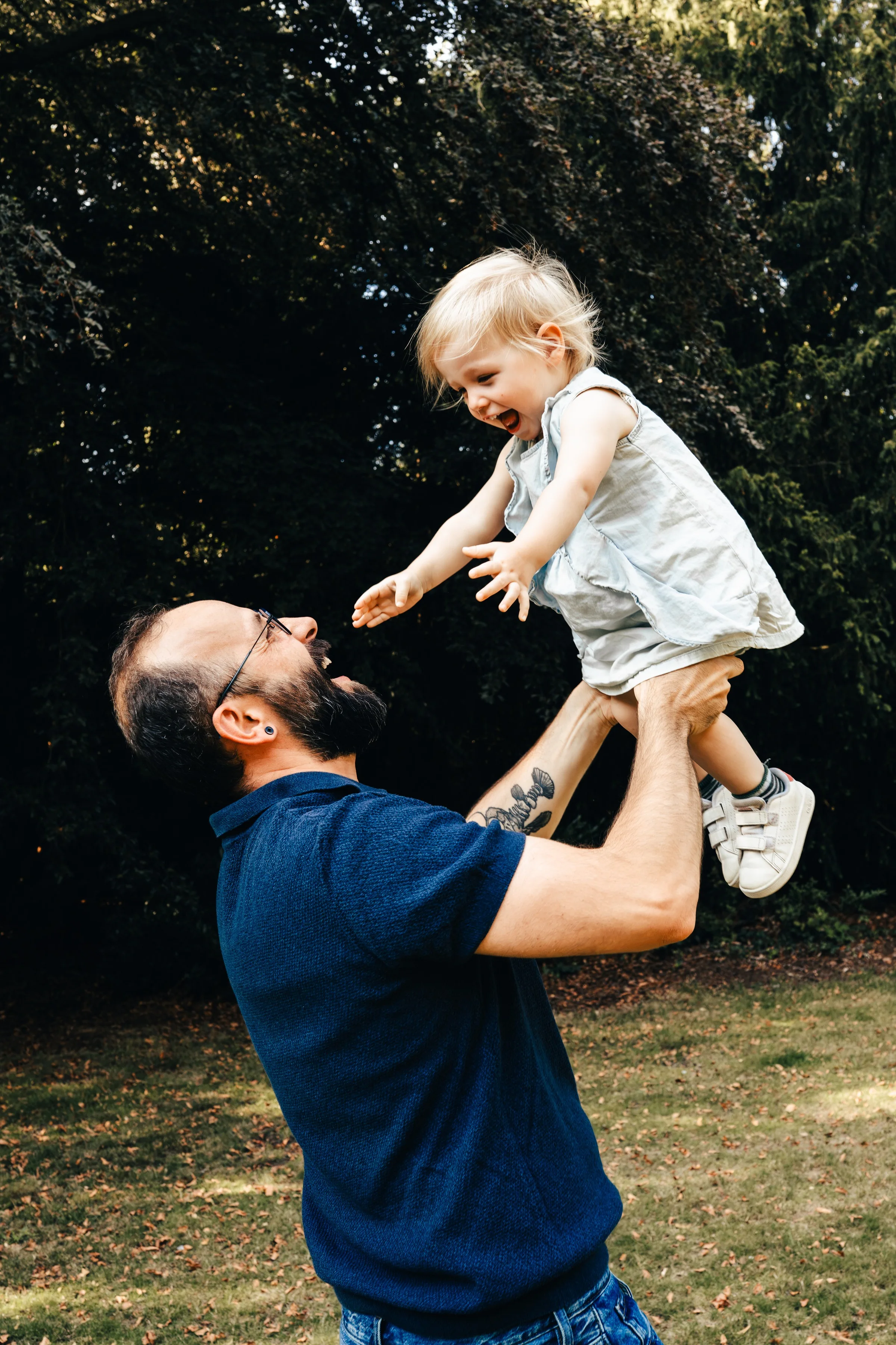 A father lifting his toddler into the air in the garden