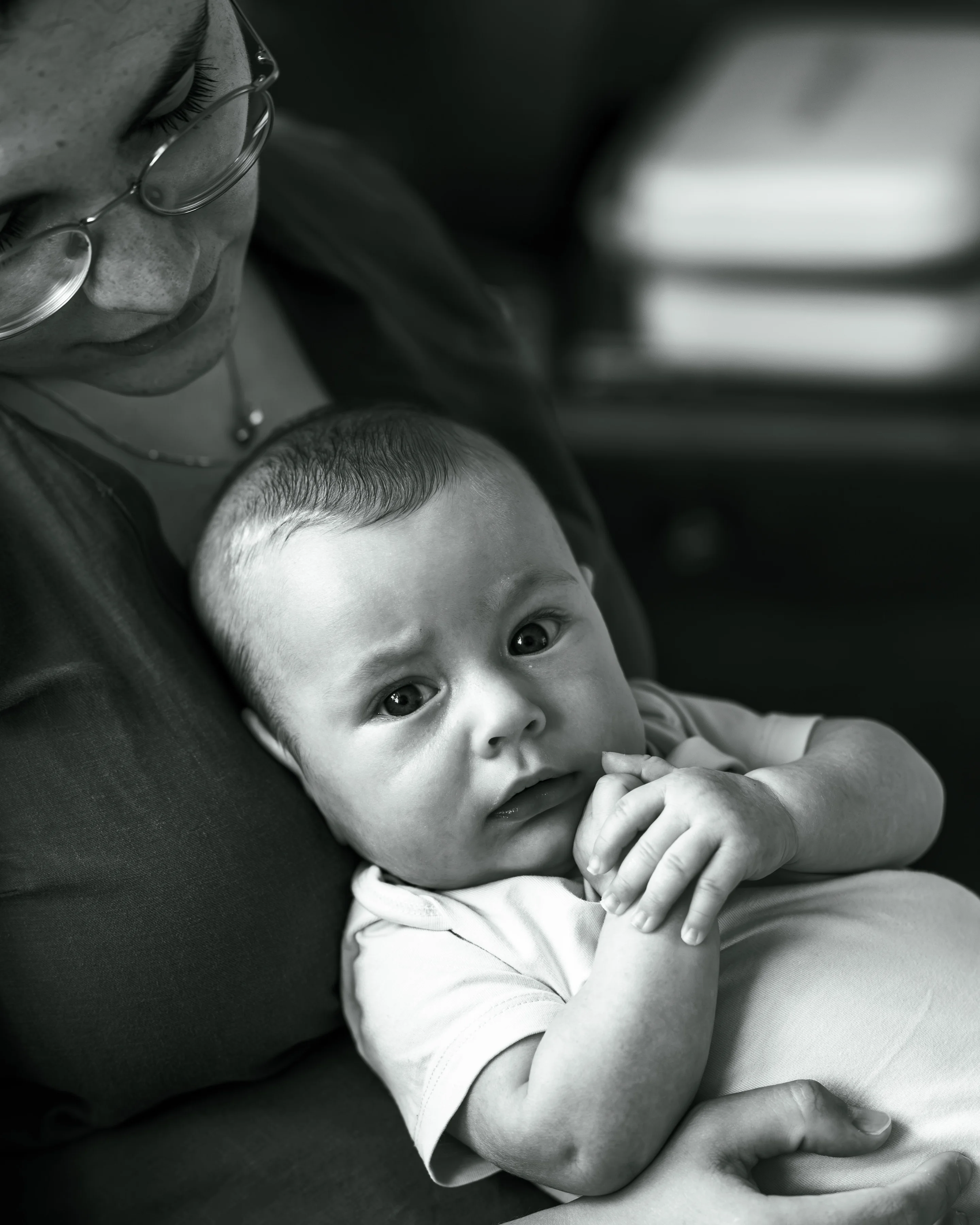 Black and white photo of a baby in a parent’s arms