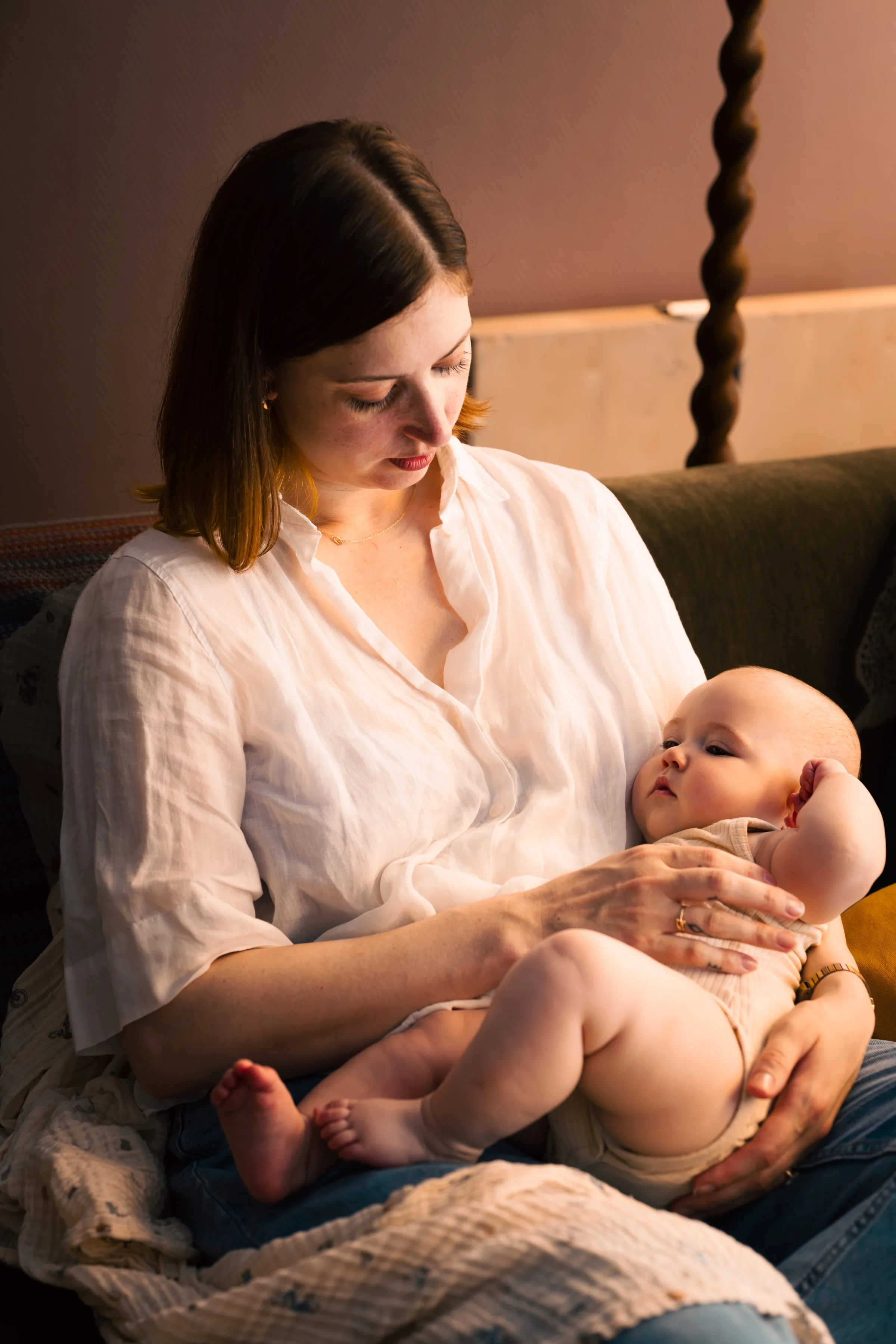 A mother cradling her baby on the sofa