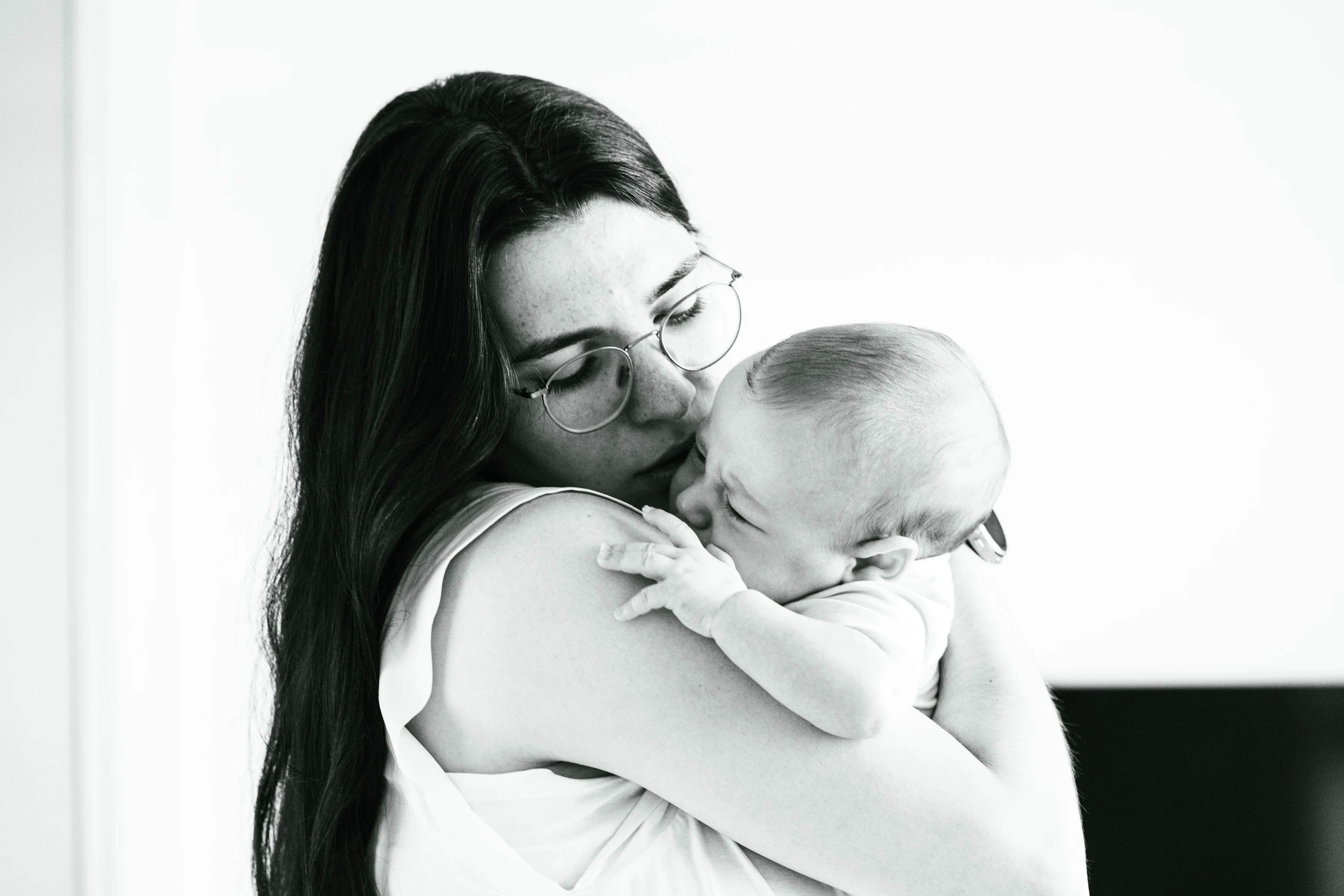 Black and white photo of a mother kissing her baby