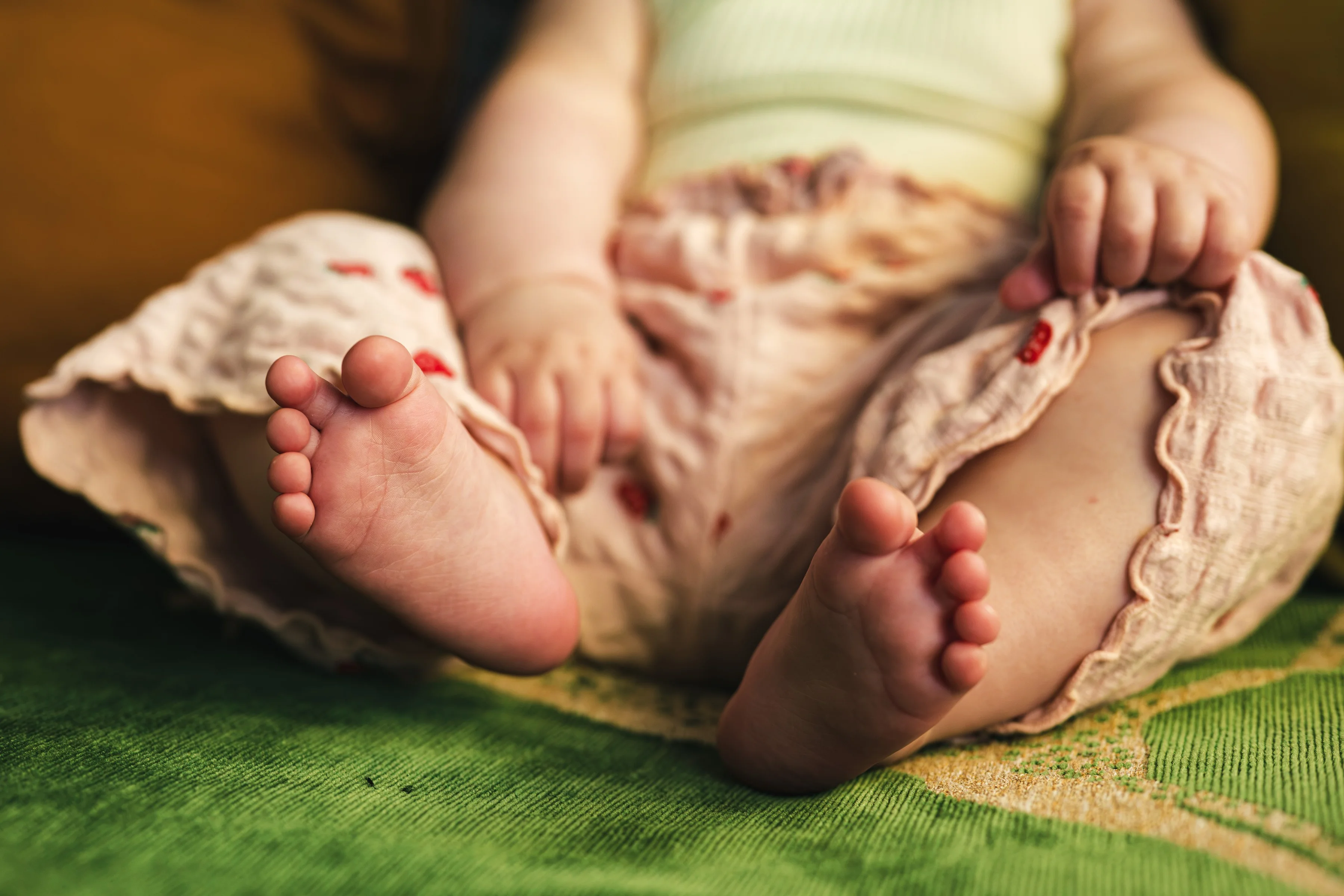 A baby’s bare feet on a green blanket