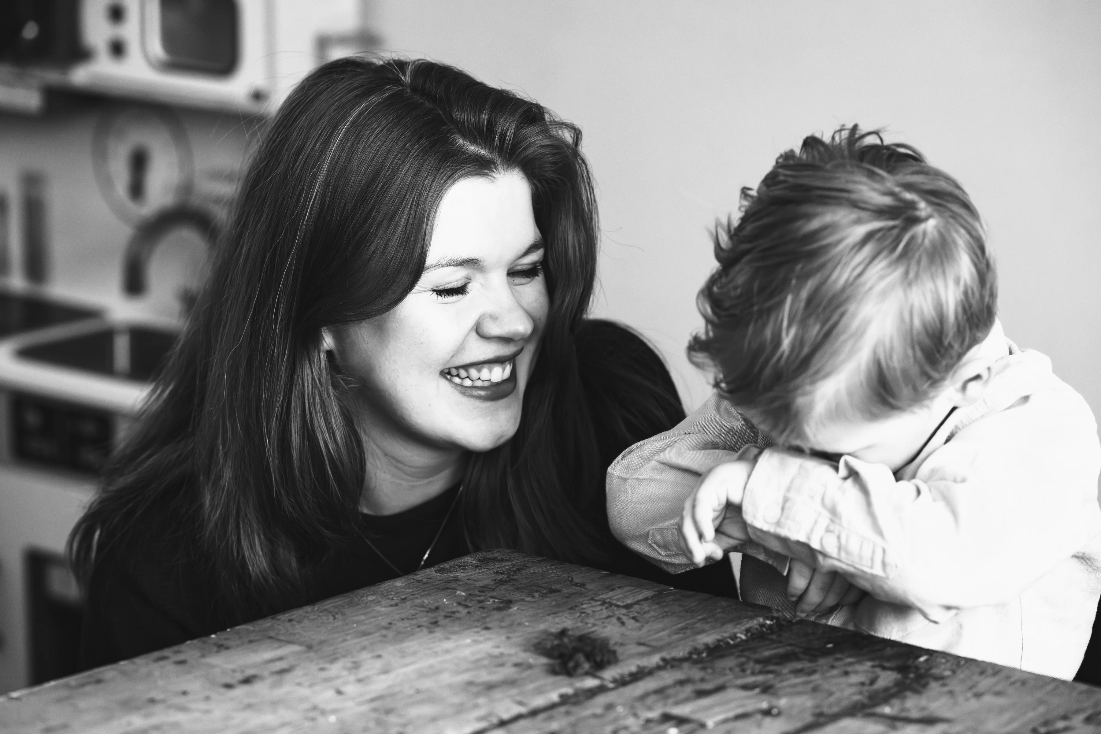 Black and white photo of a mother laughing with her son at the table