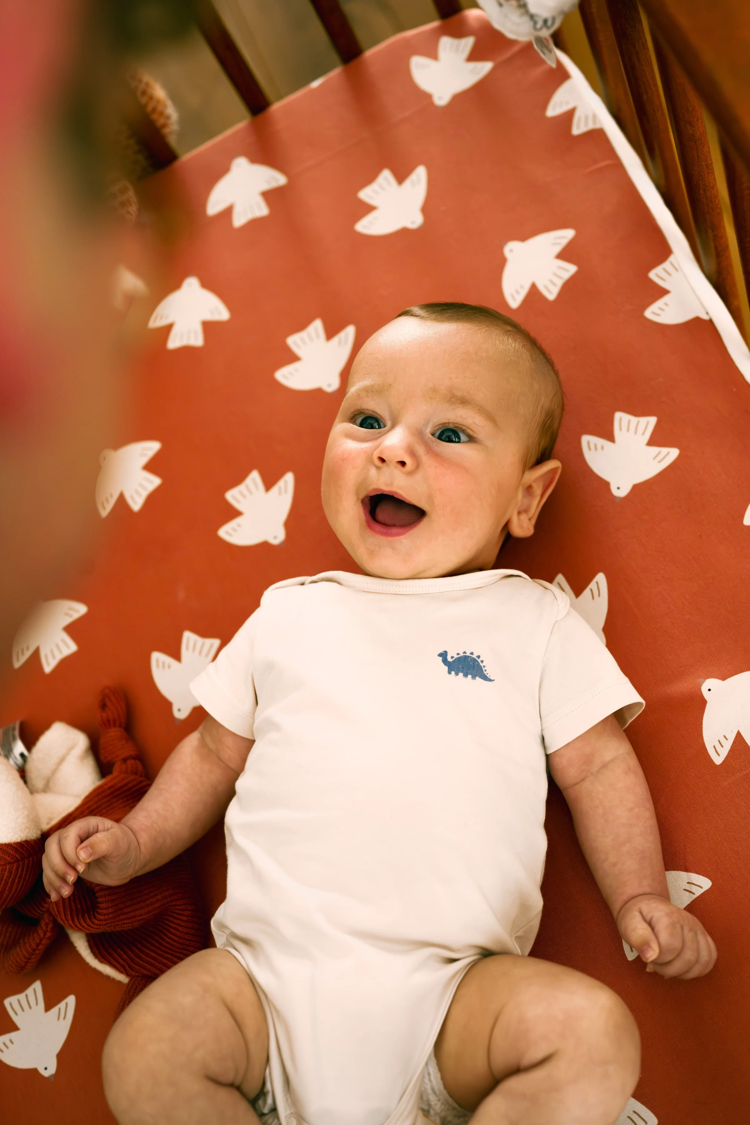 A baby smiling on an orange blanket